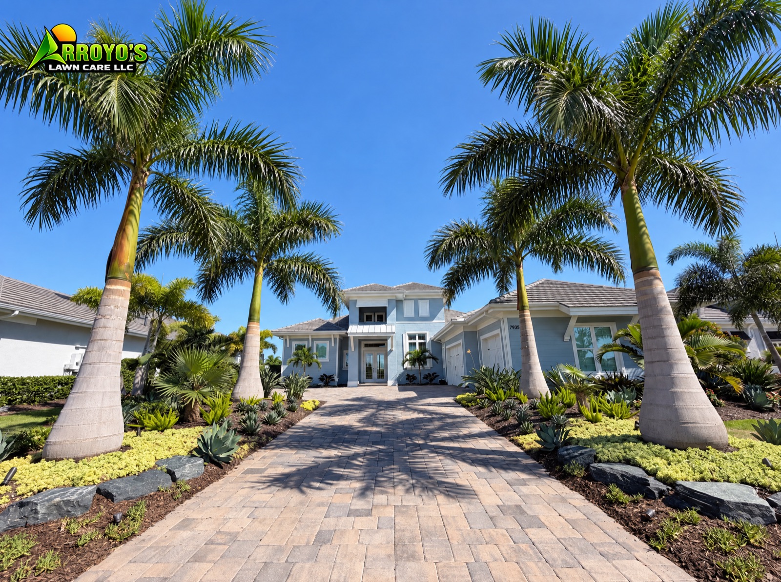 Paver driveway lined with royal palms and fresh planting beds